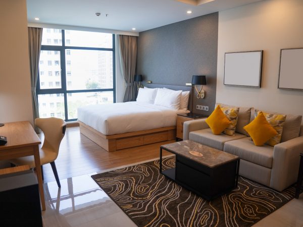 Modern studio apartment design with bedroom and living space. Hotel room panoramic window, king sized bed, couch and coffee table. City flat concept